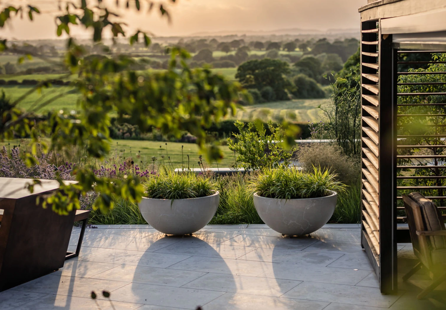 Photo of a landscaped garden with freestanding planters and a wood trellis