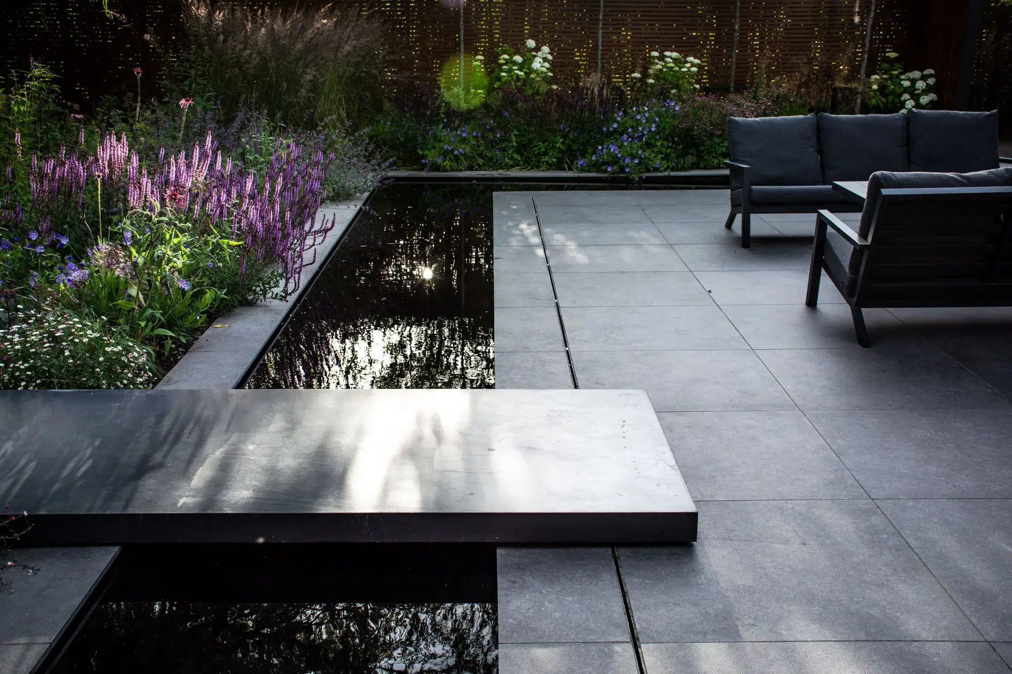 Modern terrace with water feature and purple planting.
