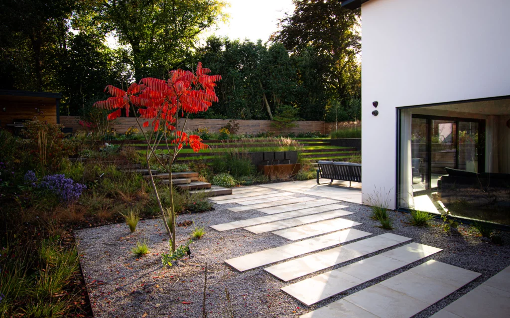Stepped stone pathway with colourful planting and tiered lawn terraces.