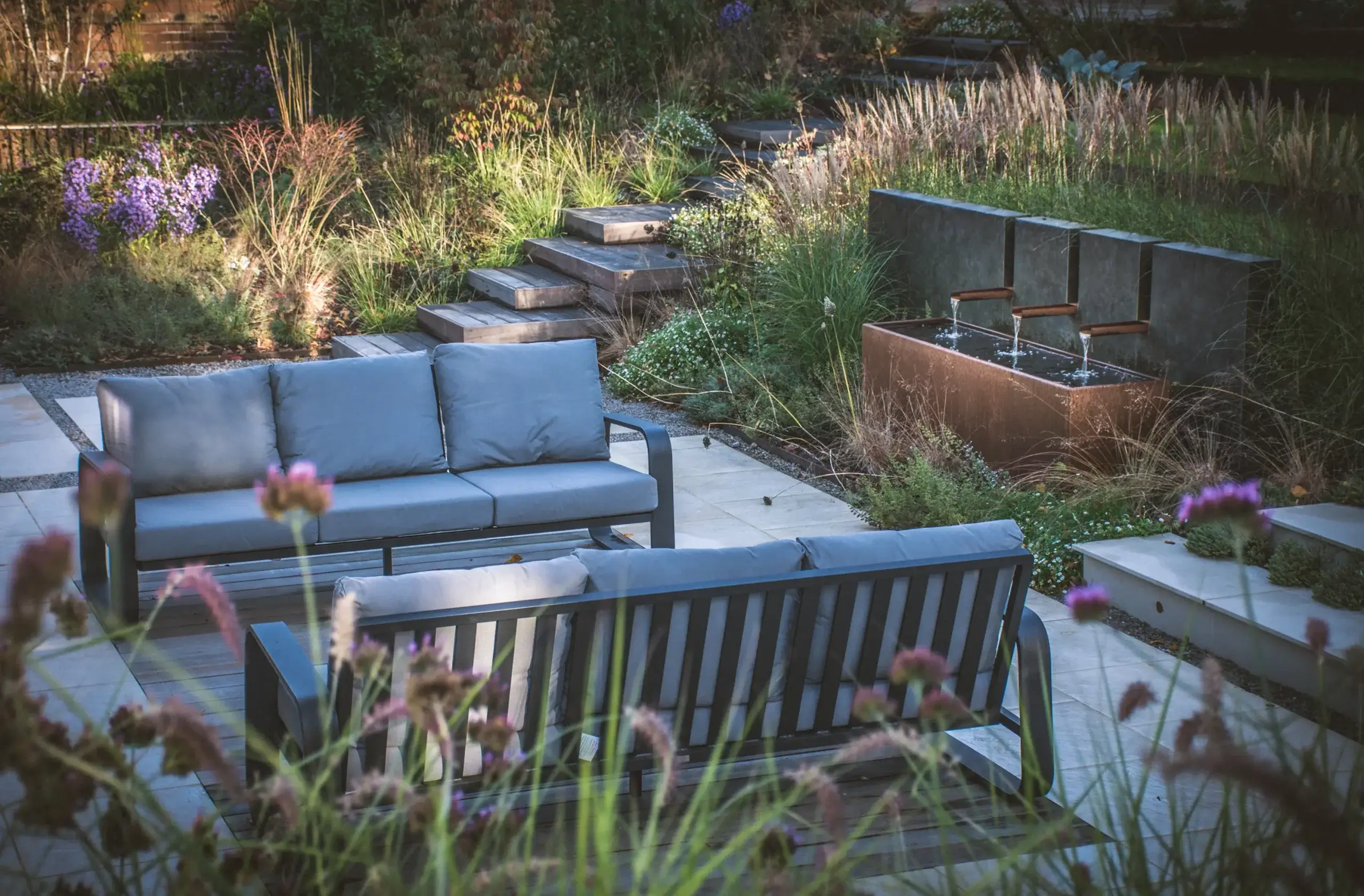 Outdoor seating area with timber steps and water feature.