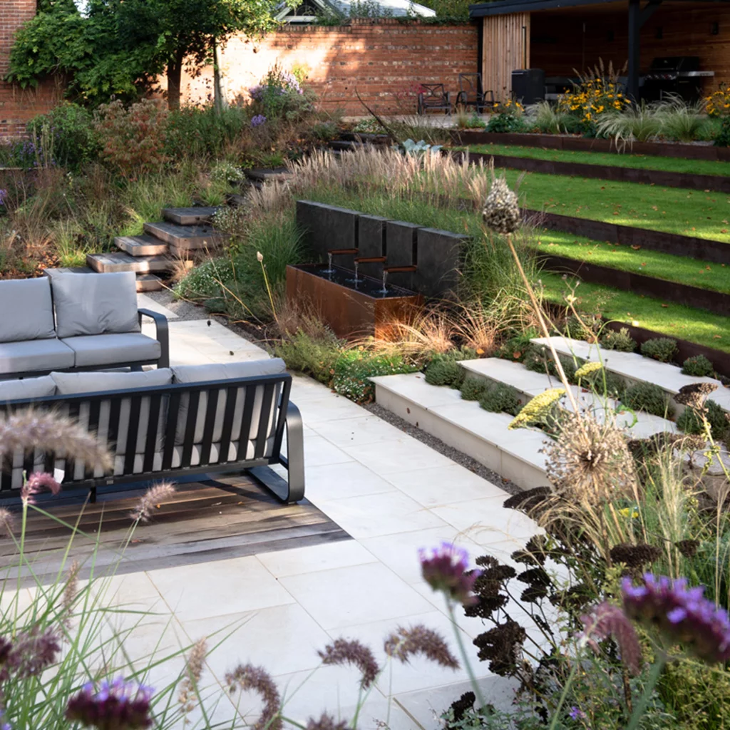 Tiered garden with stone steps, seating area, and water feature.