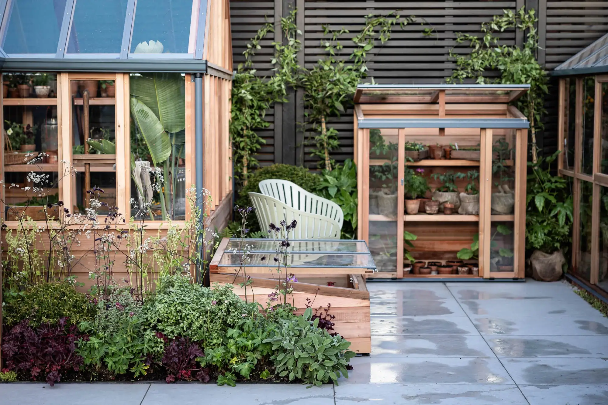 Modern greenhouse garden with raised beds and potted plants.