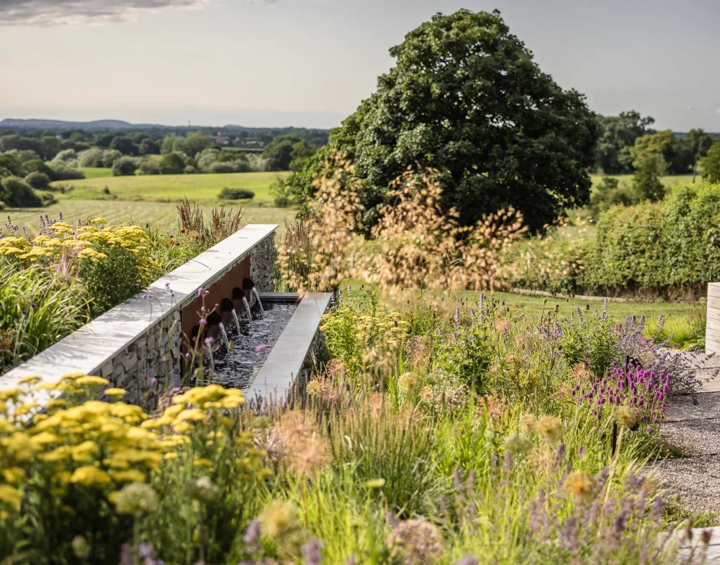 Wildflower planting with a modern stone water feature and countryside views.