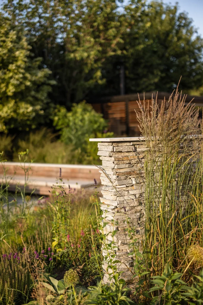 Contemporary garden with stacked stone pillar and naturalistic planting.