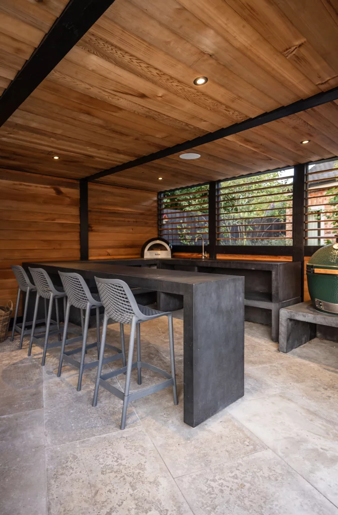 Outdoor kitchen with bar seating and timber cladding.