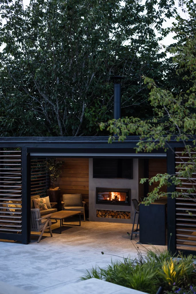 Outdoor seating area with fireplace and timber clad structure.